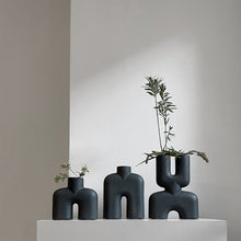 Load image into Gallery viewer, Group of Tall black two-legged ceramic vase for holding flowers
